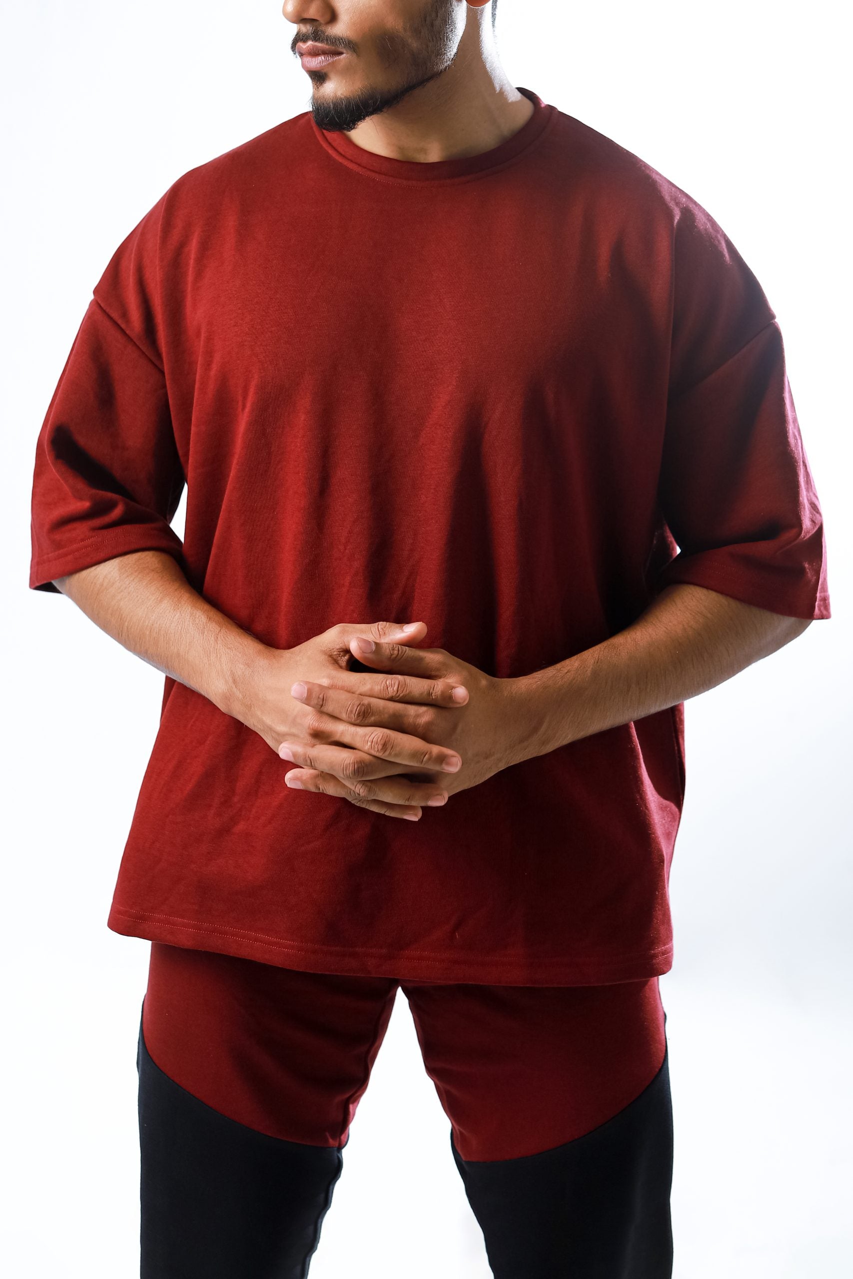 A person standing, wearing Gym stereo red oversized T-shirt and black pants.