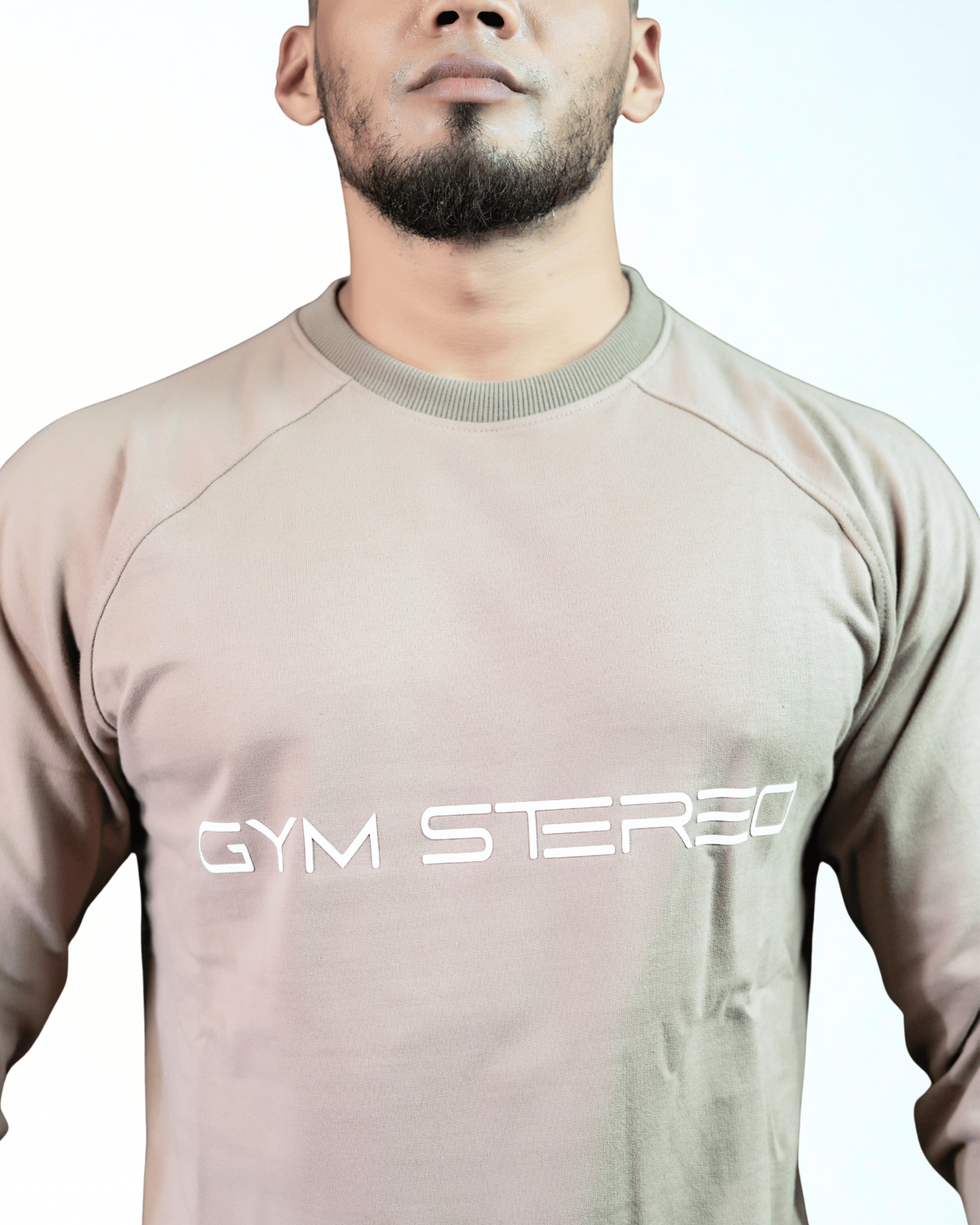 Person wearing a beige long-sleeve shirt with 'GYM STEREO' text on a white background