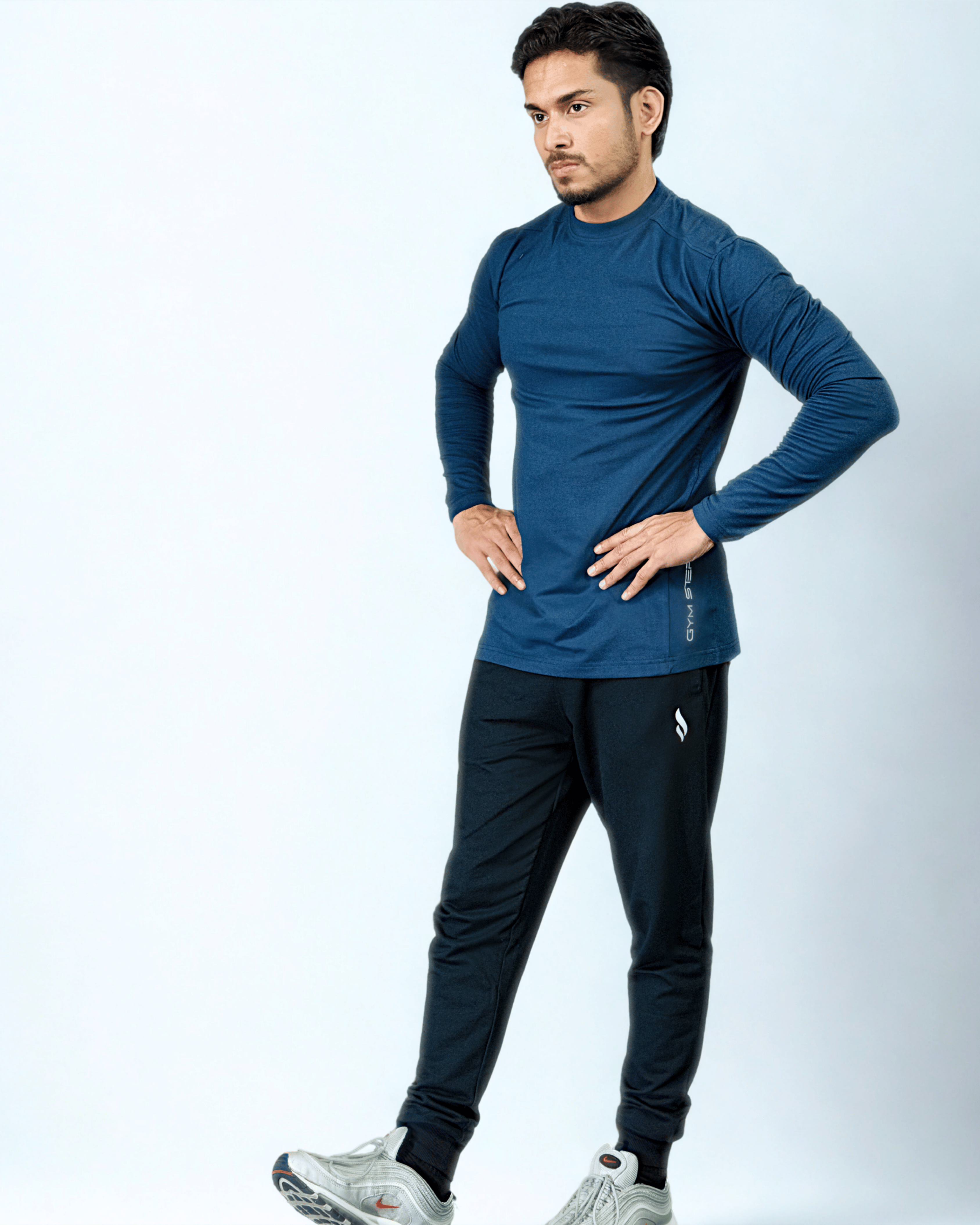 Man wearing a blue long-sleeve shirt and black pants on a white background